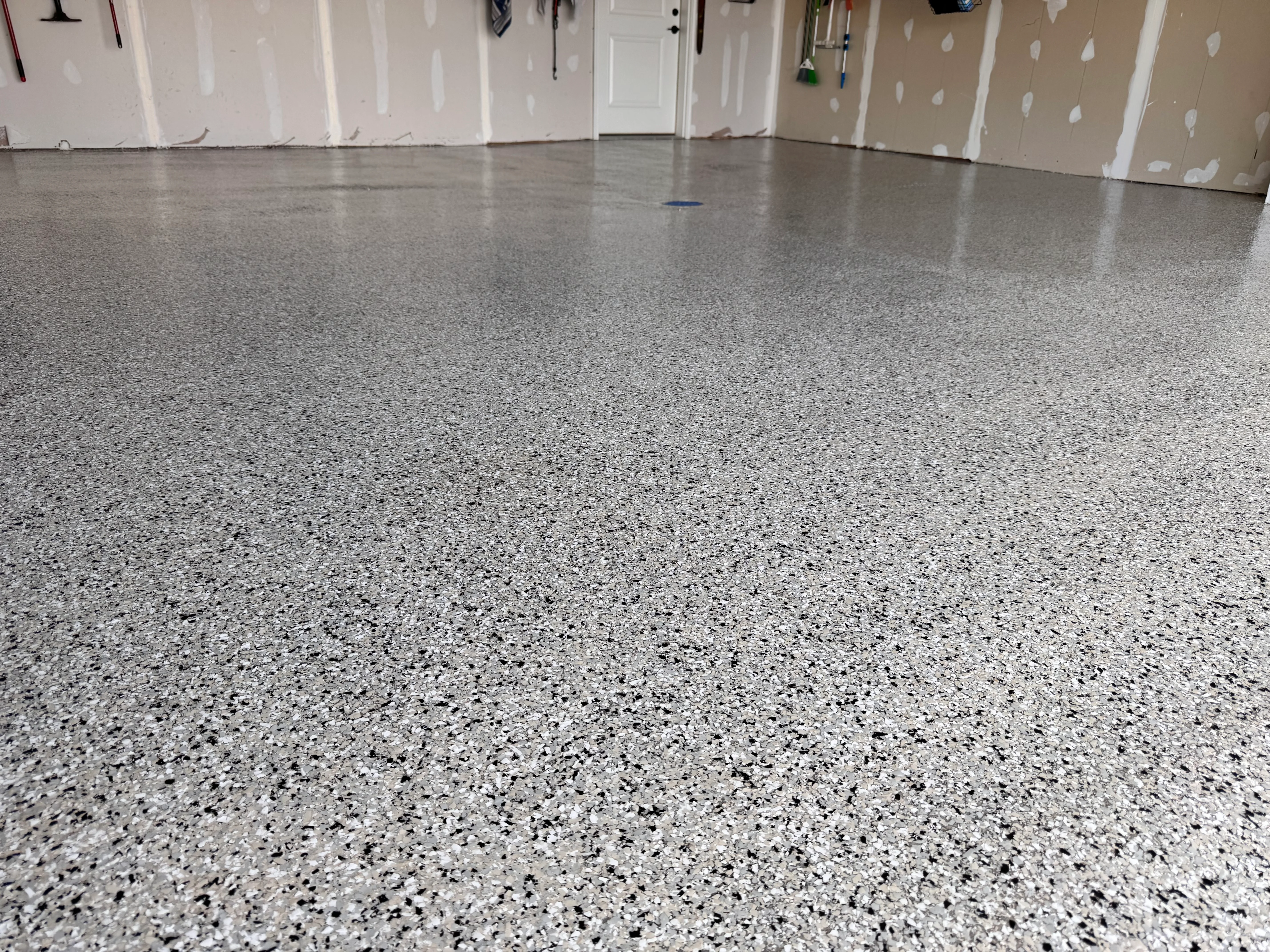 Gray speckled epoxy garage floor with glossy finish and white walls
