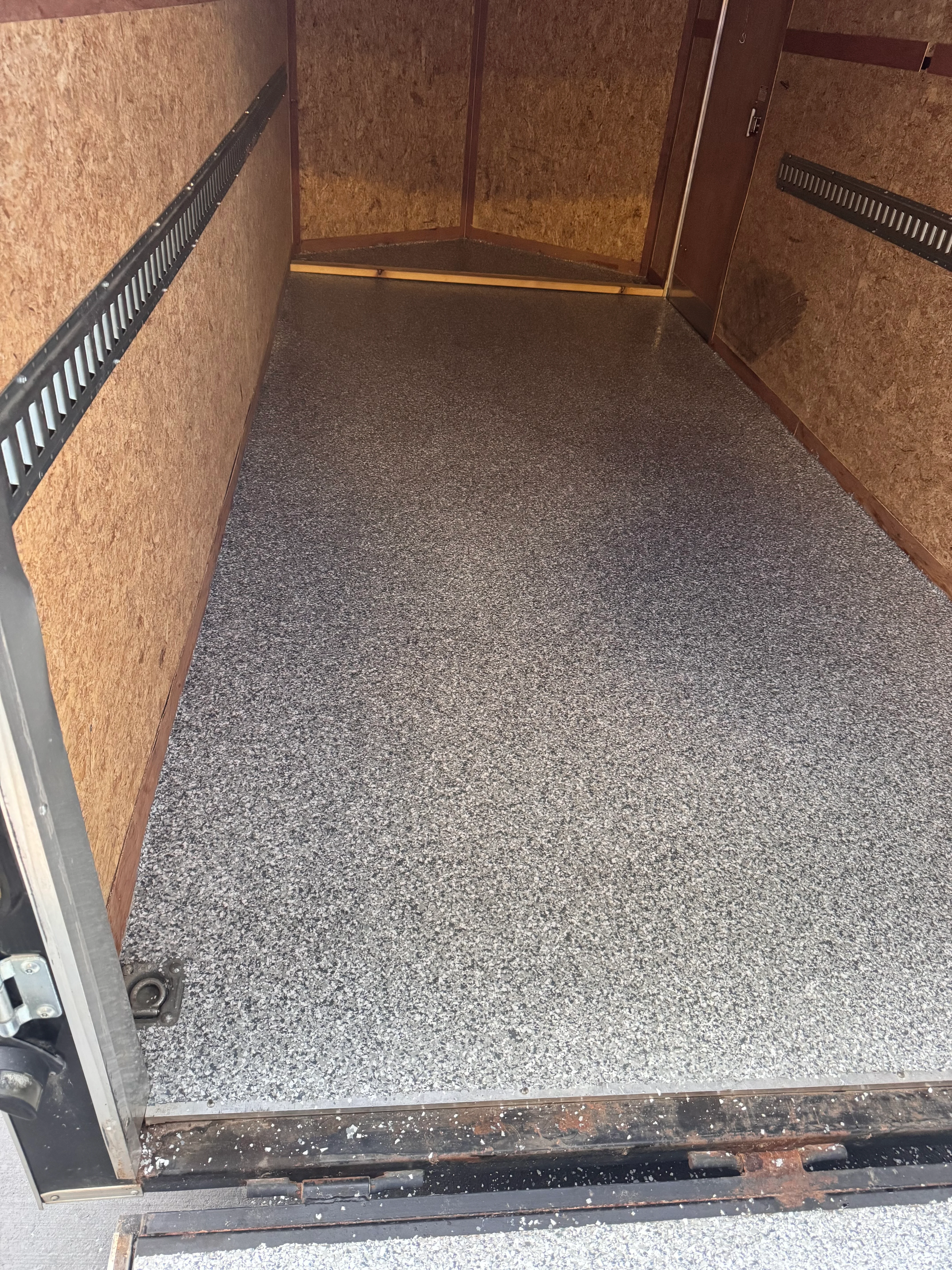 Gray speckled epoxy floor in enclosed trailer with cork walls and black trim