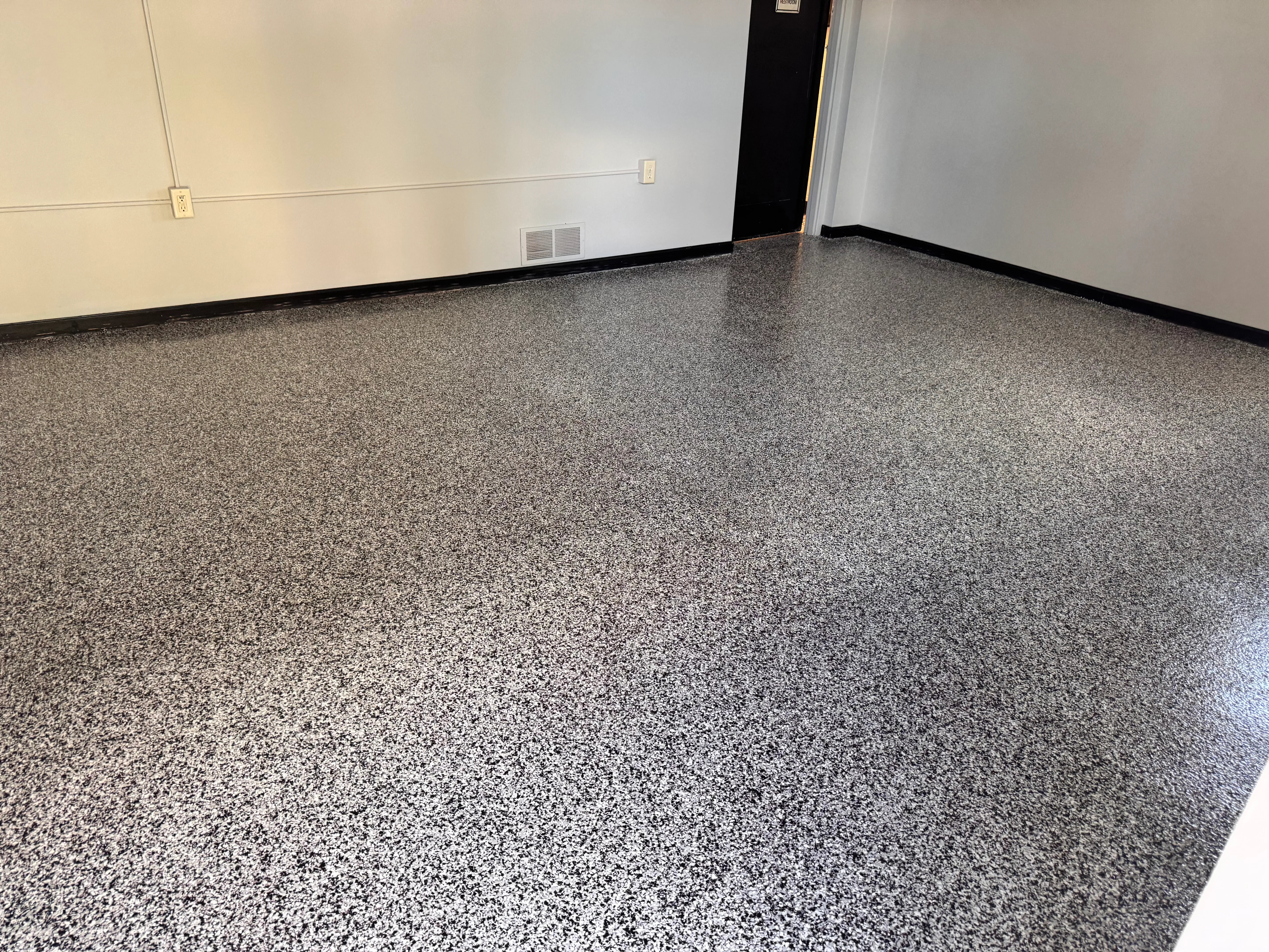 Gray speckled epoxy floor with black trim in commercial space