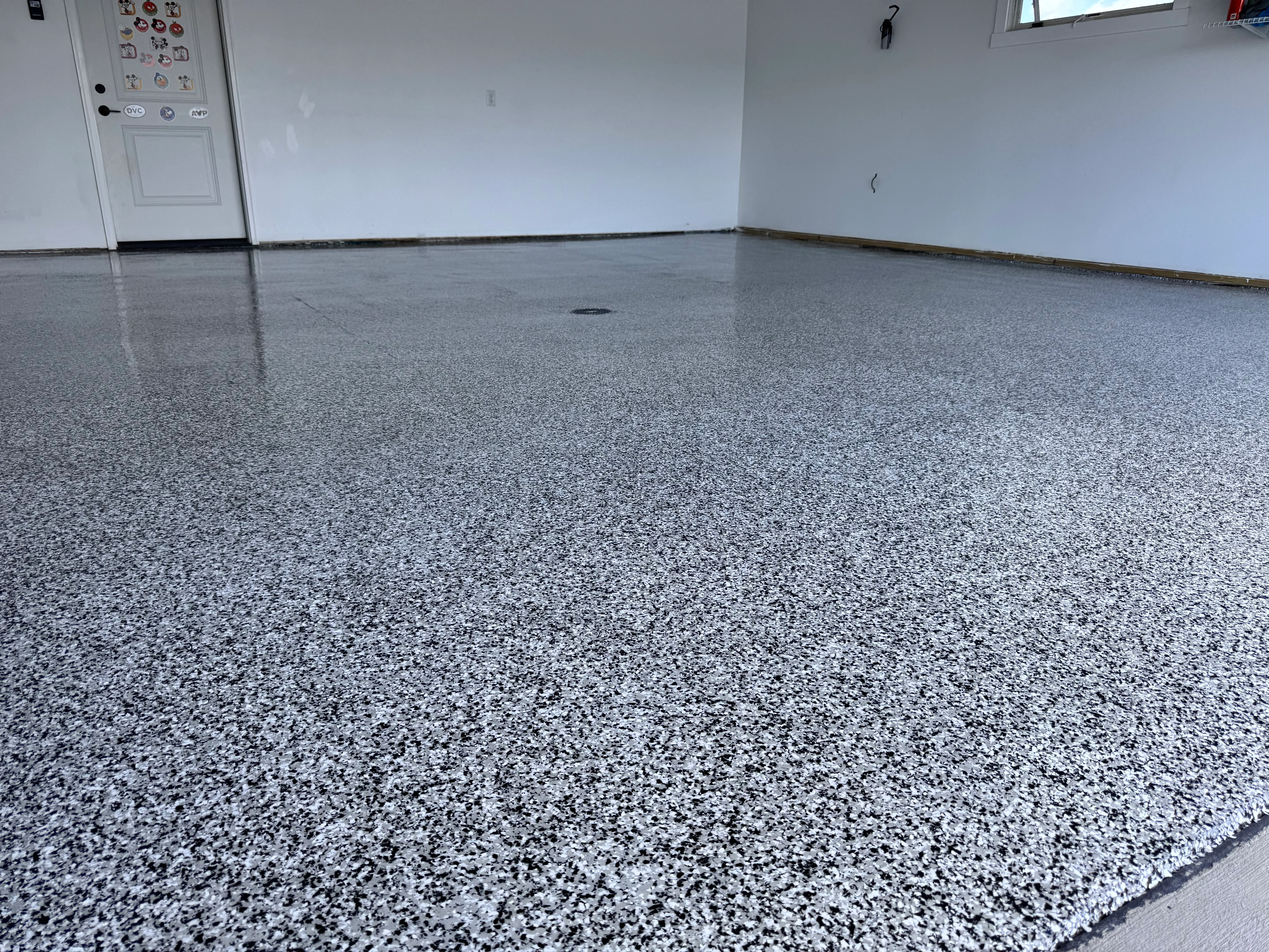 Gray speckled epoxy garage floor with glossy finish and clean edges