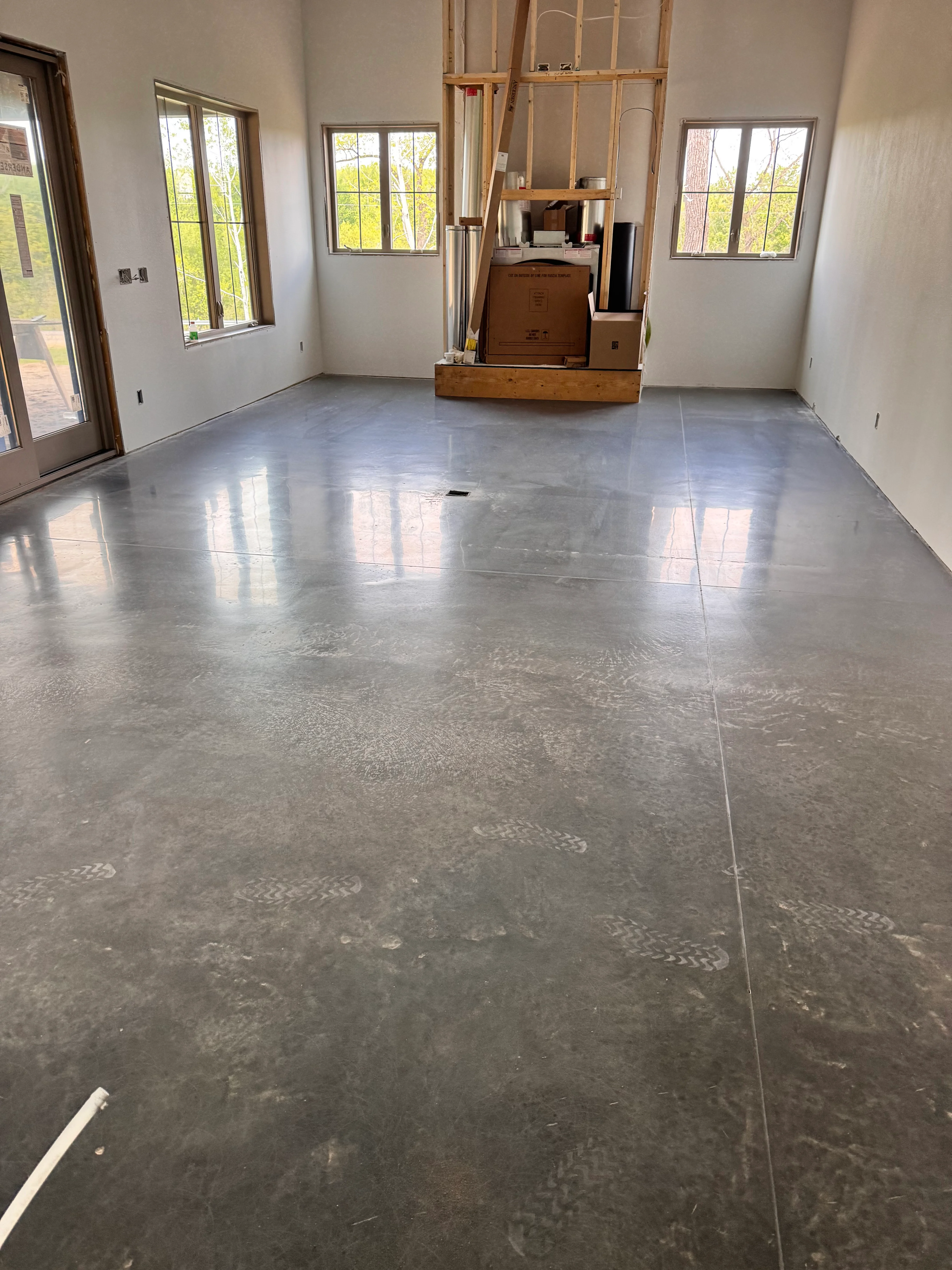 Polished concrete floor with reflective finish and control joints in bright room with windows