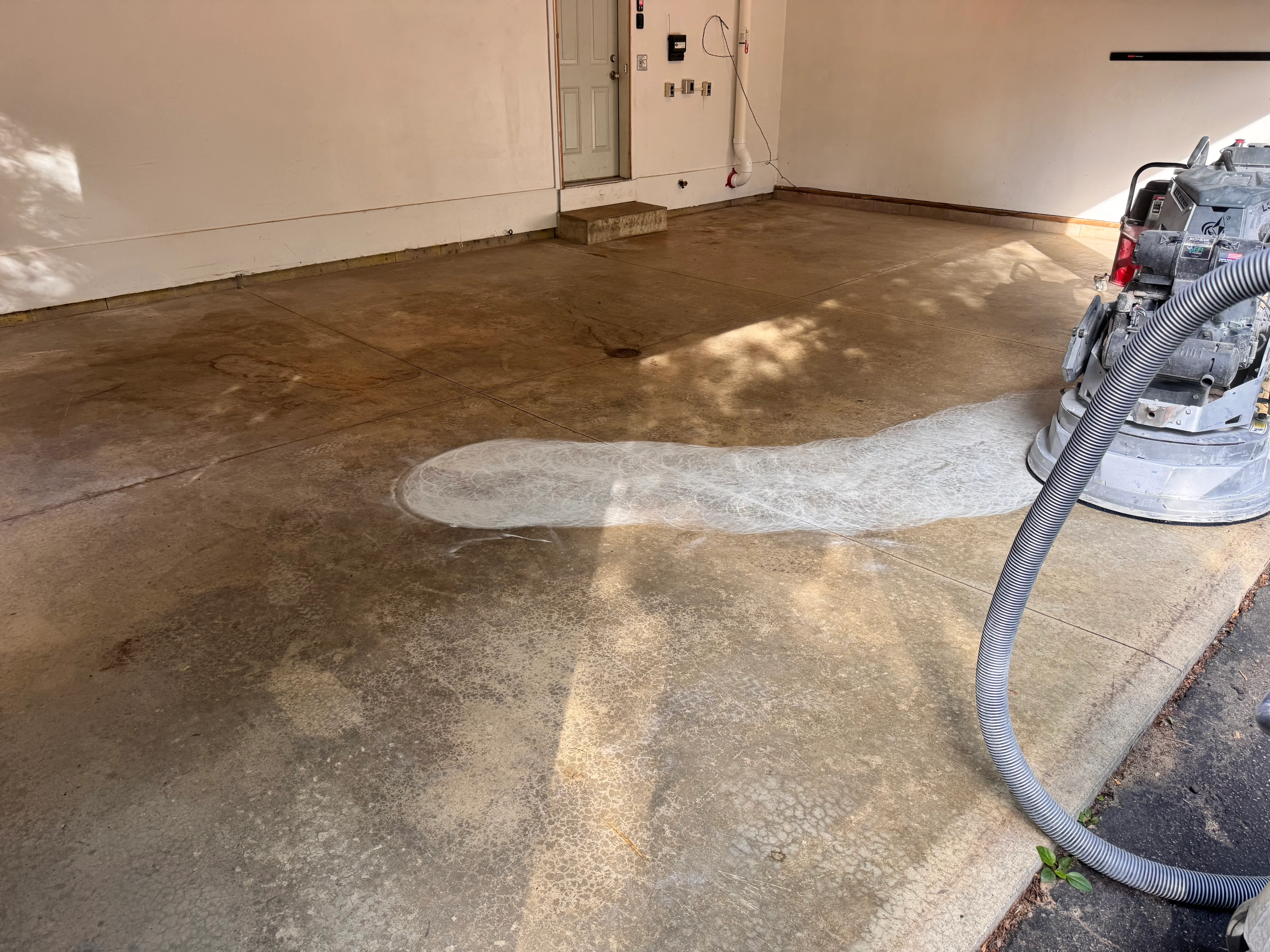 Garage epoxy floor installation in progress with sealed concrete surface and equipment