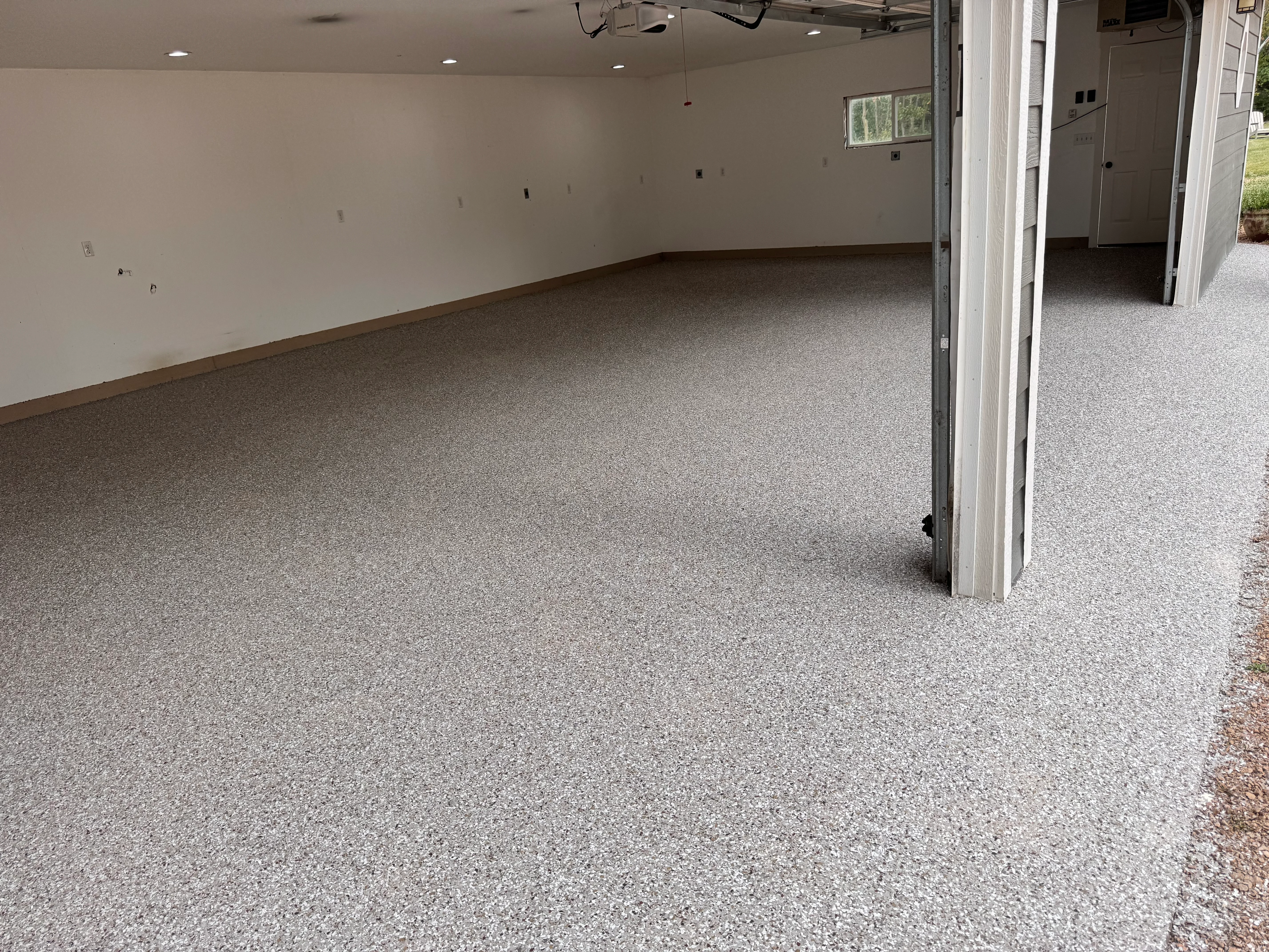 Light gray speckled epoxy garage floor with brown trim in finished residential space