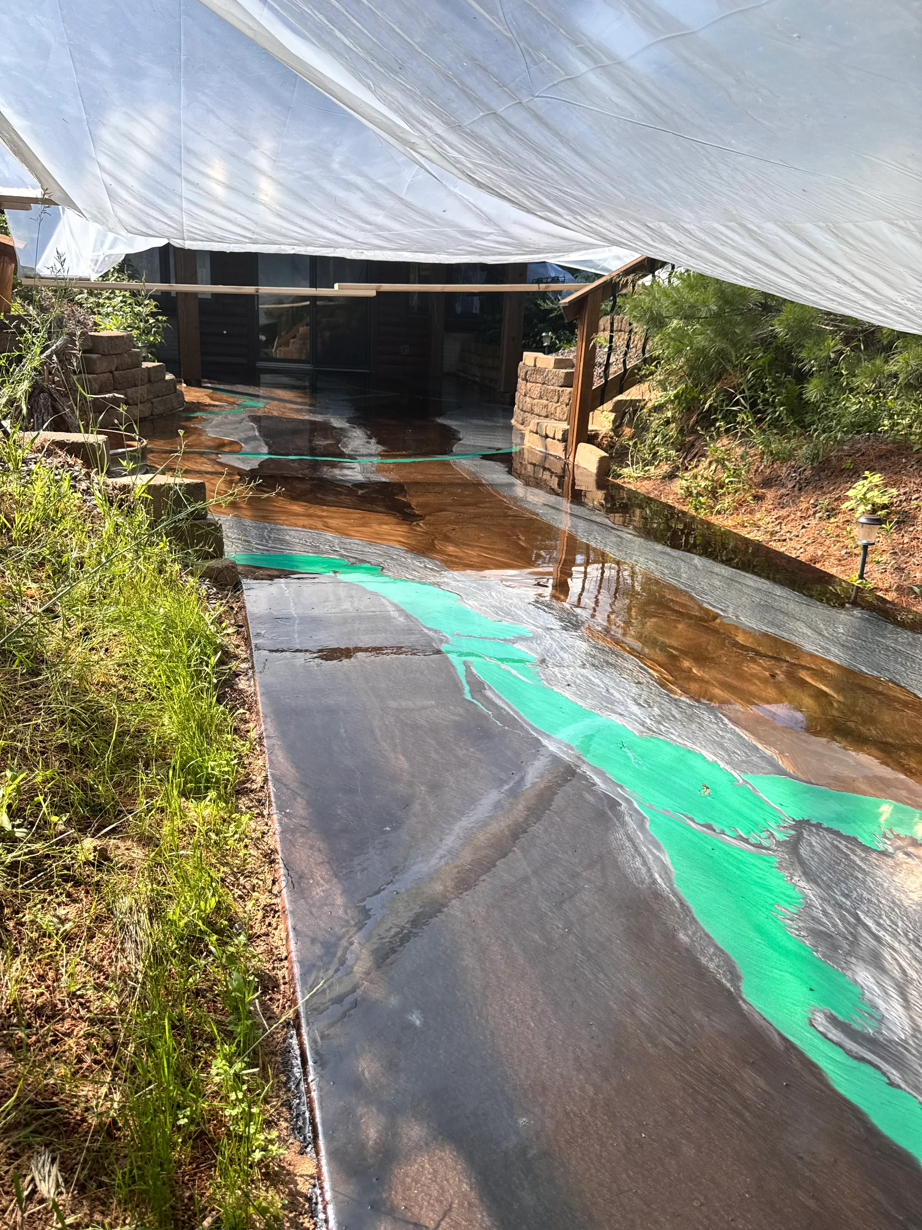 Epoxy flooring with bright green striping pattern on concrete surface under white shade cloth