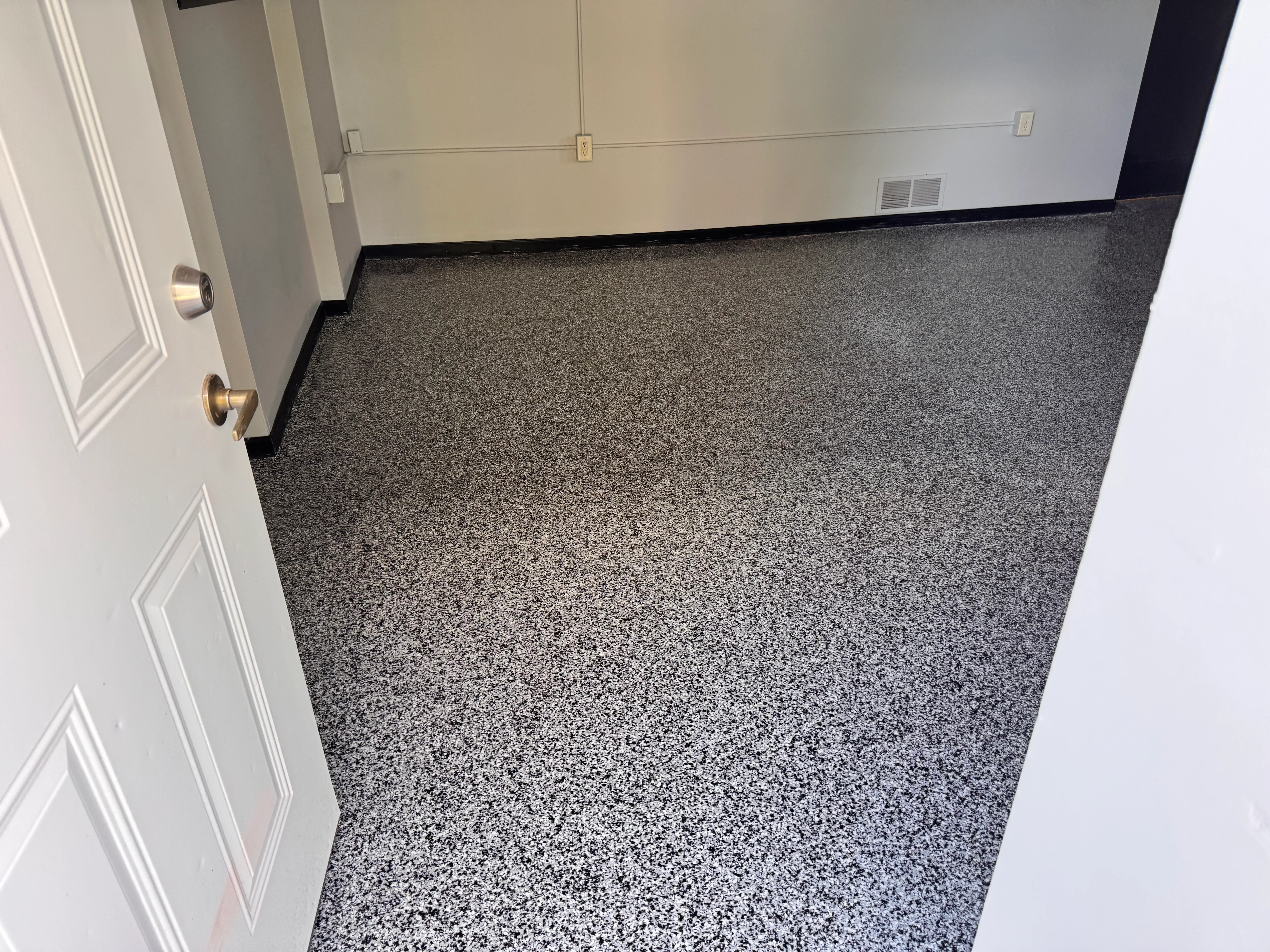 Speckled gray epoxy floor with black trim and white walls in commercial space