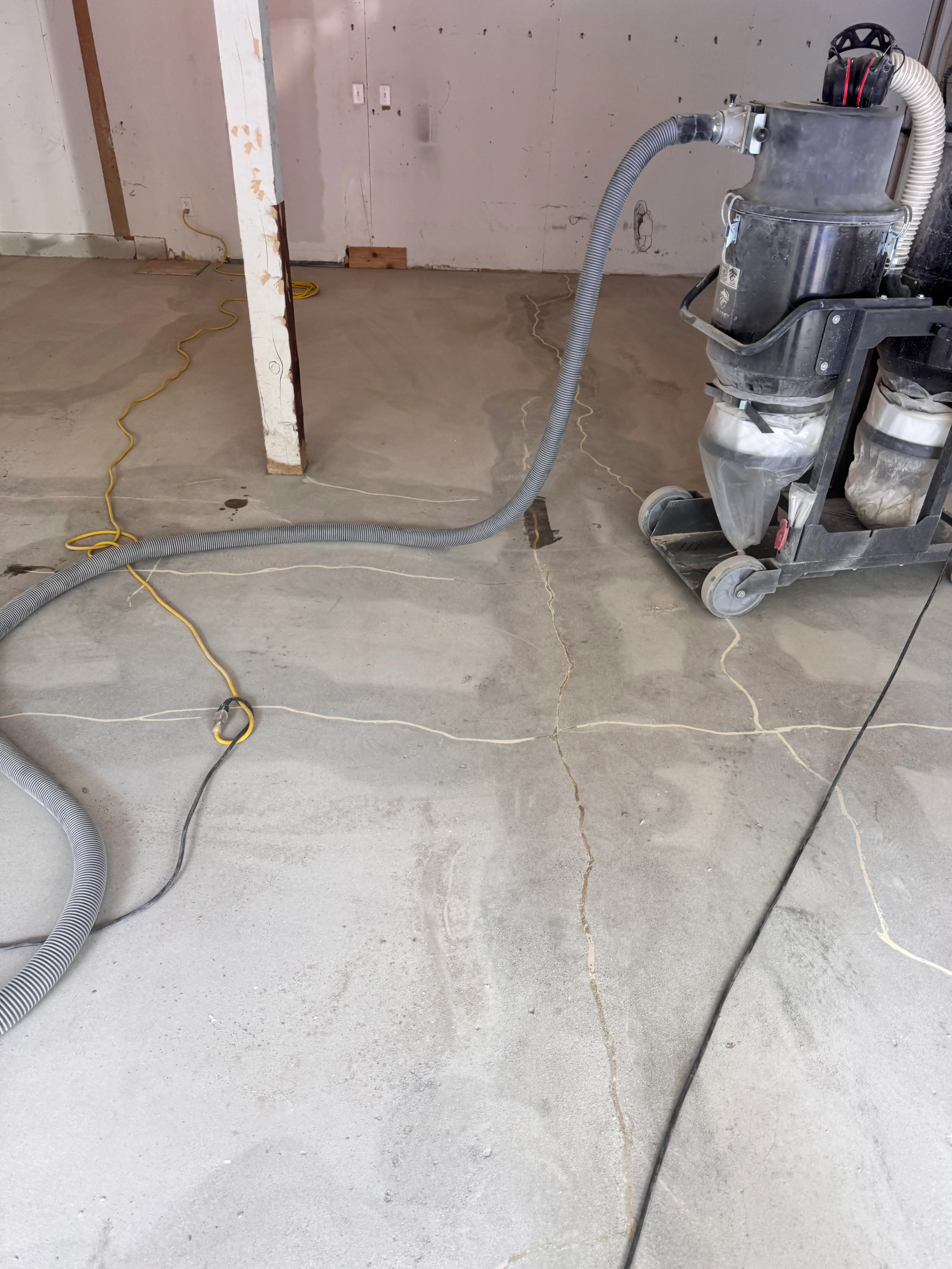 Basement concrete floor marked with chalk lines during epoxy prep work with wet vacuum equipment