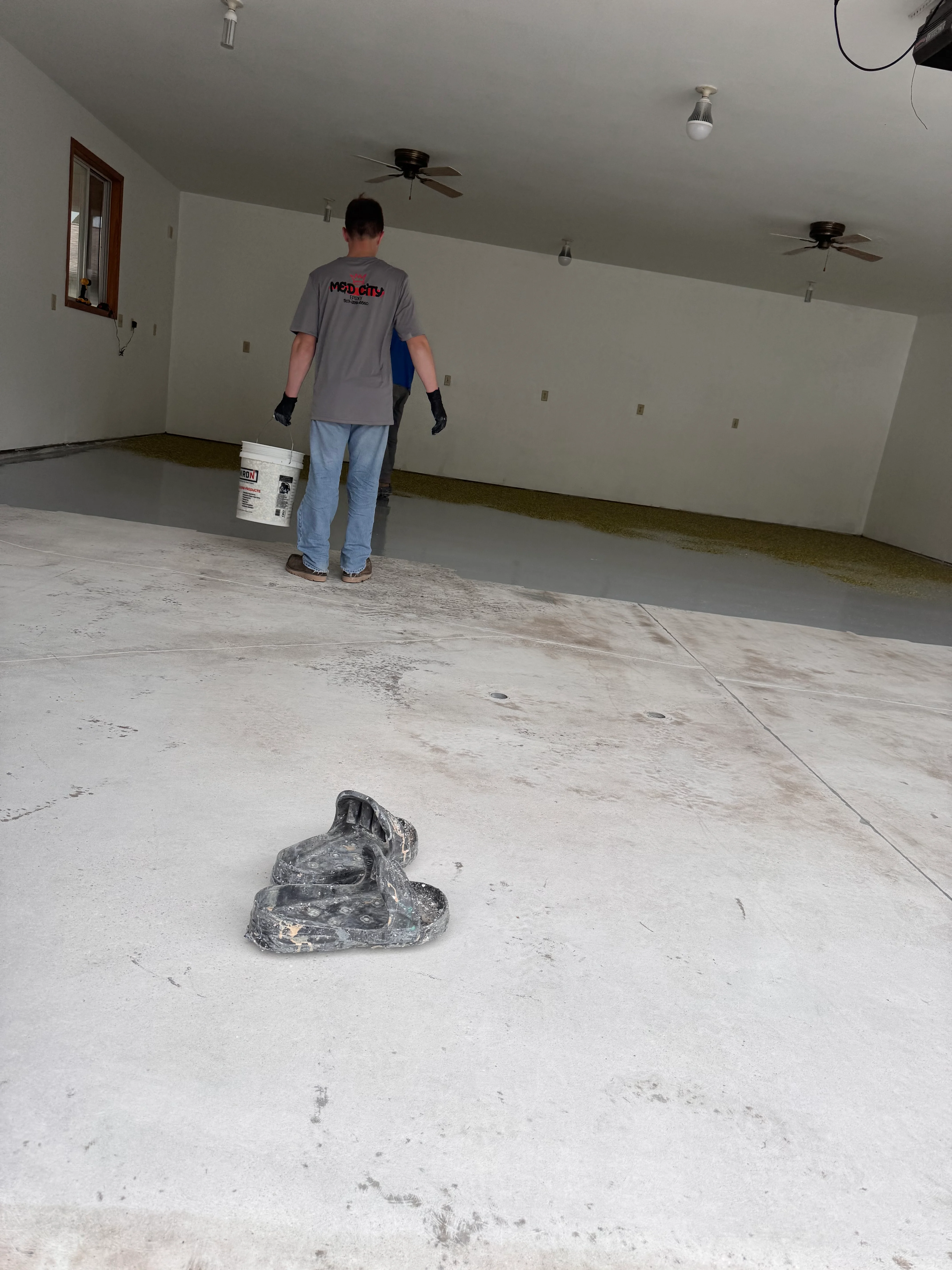 Garage epoxy flooring prep with worker and concrete surface ready for coating application