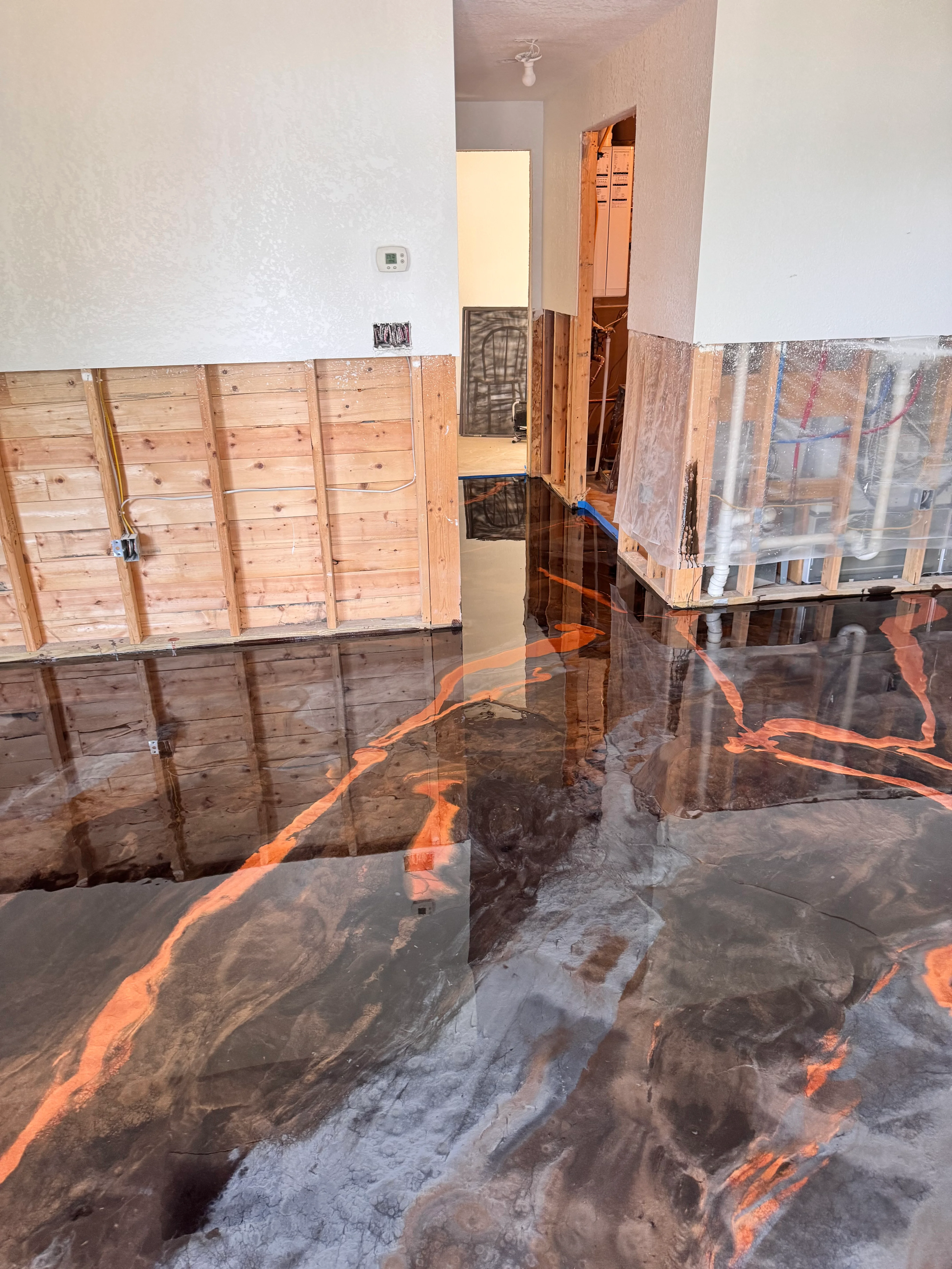 Metallic epoxy floor with orange and copper veining, high-gloss finish, protective coverings during installation