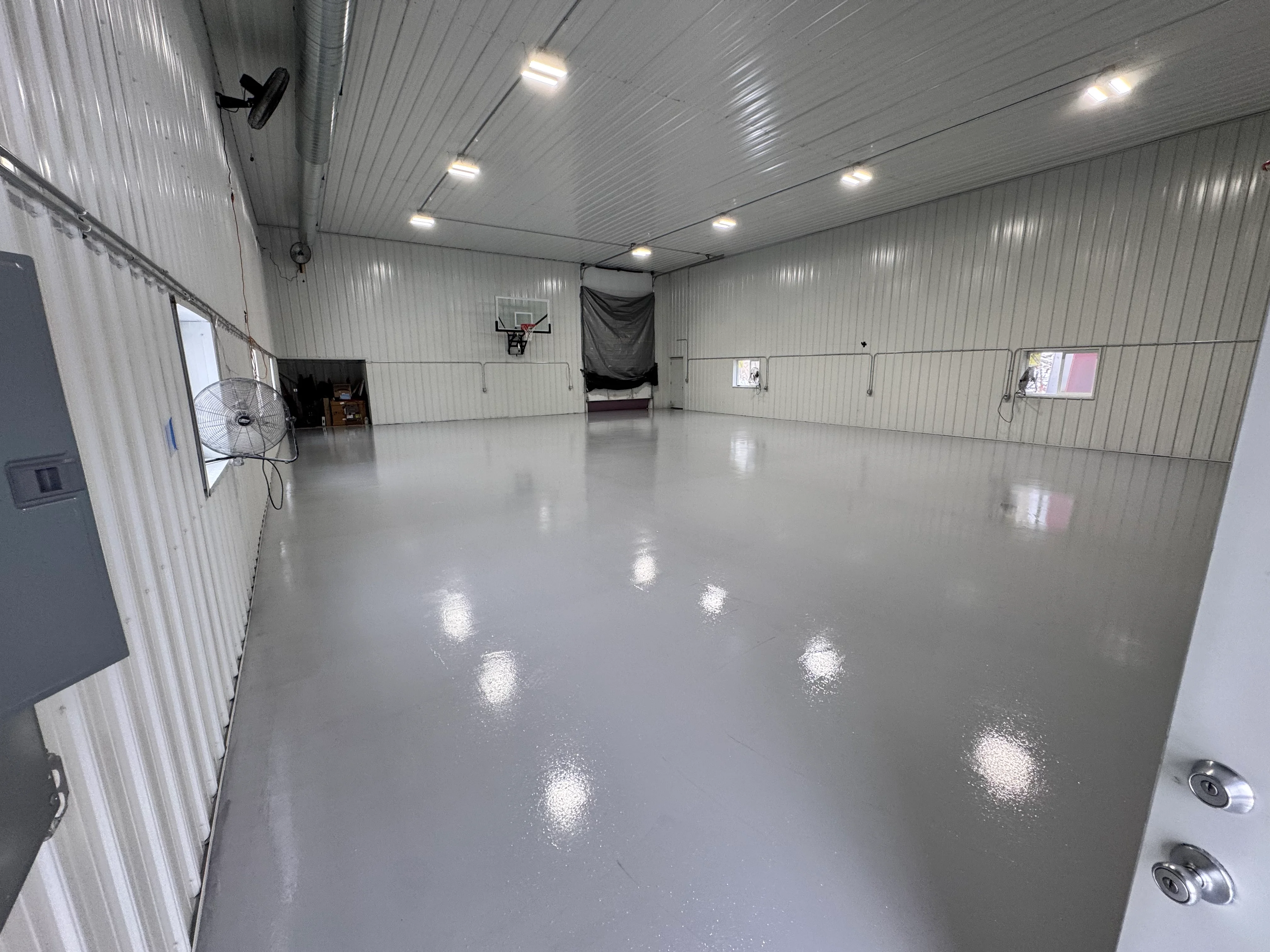 Polished gray epoxy garage floor with LED ceiling lights and metal walls